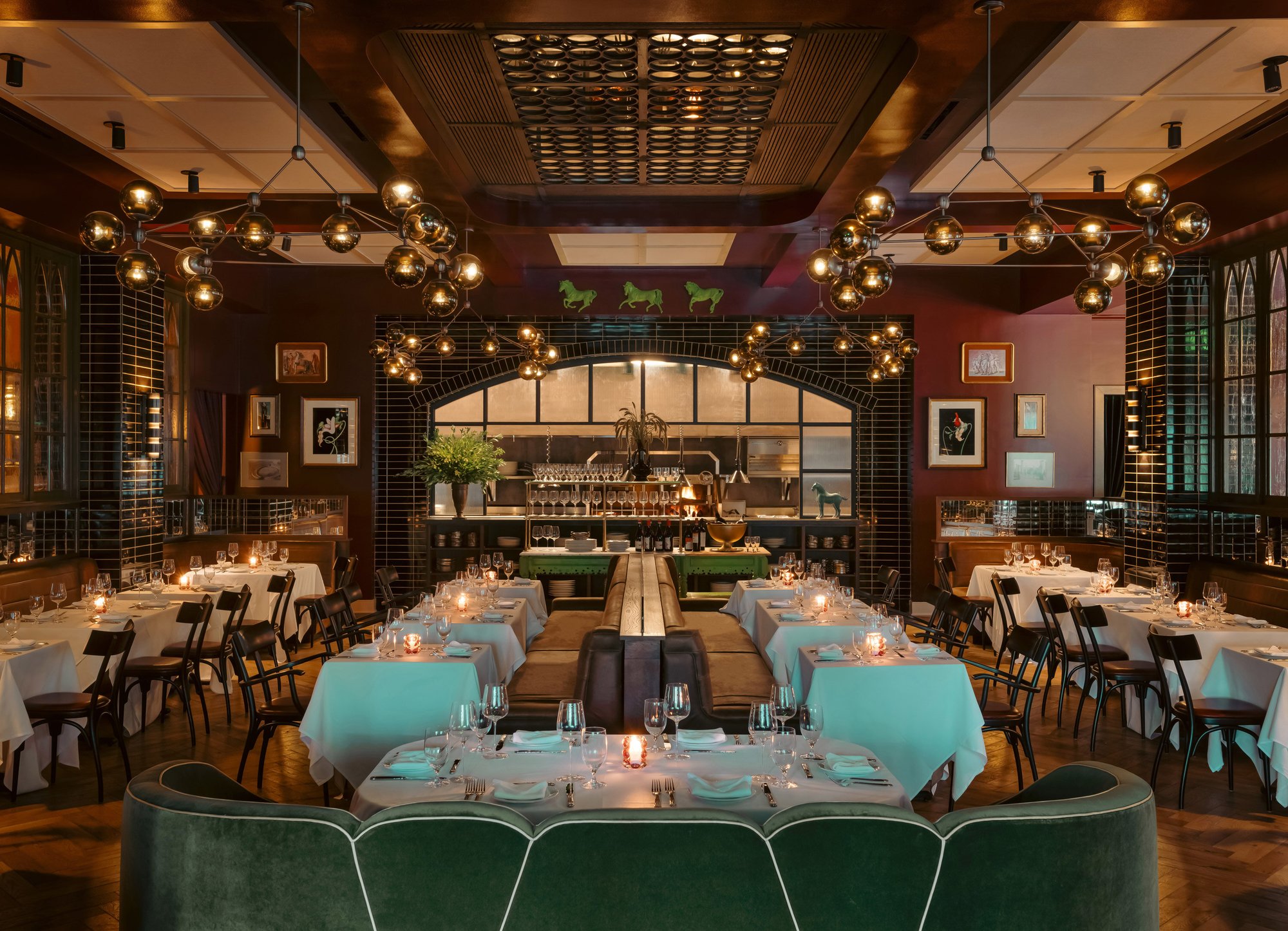 Il Premio’s dining room with green banquettes, white linen and clustered globe lights